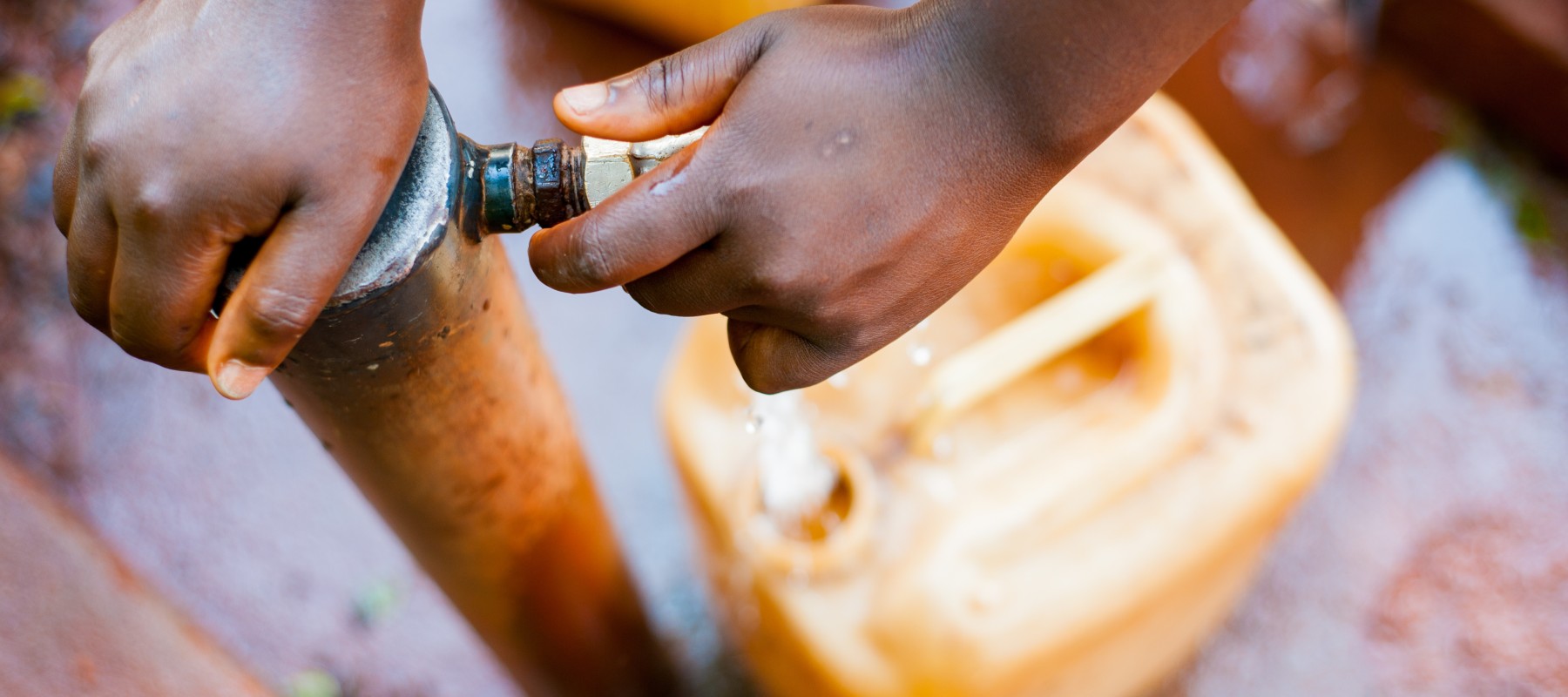 Hands on a water pump with a jerry can