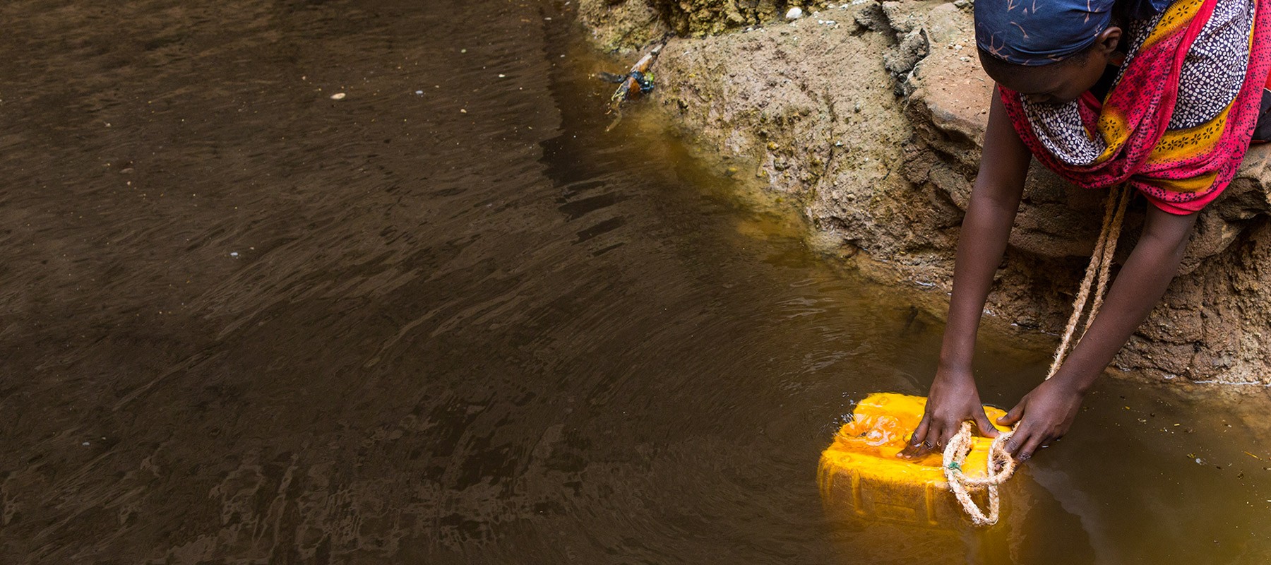 A lady collecting water in a jerry can