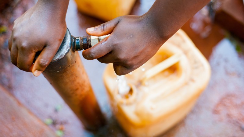Hands on a water pump with a jerry can